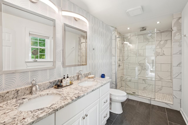 bathroom featuring a shower stall, toilet, a sink, and double vanity