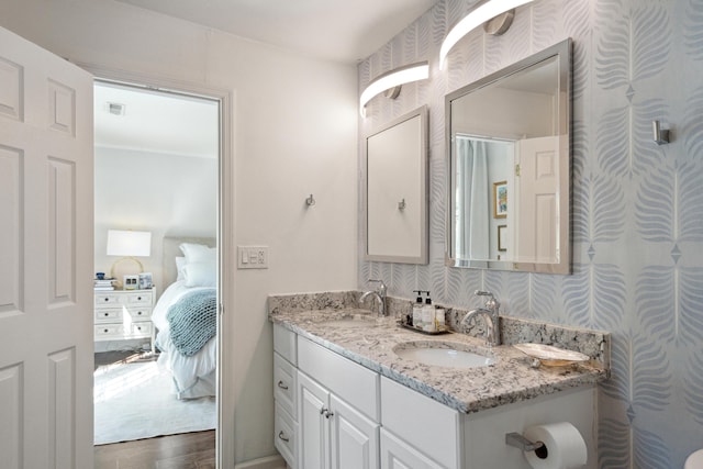 ensuite bathroom with wallpapered walls, ensuite bathroom, and a sink