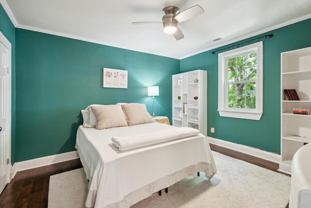 bedroom featuring baseboards, wood finished floors, visible vents, and crown molding