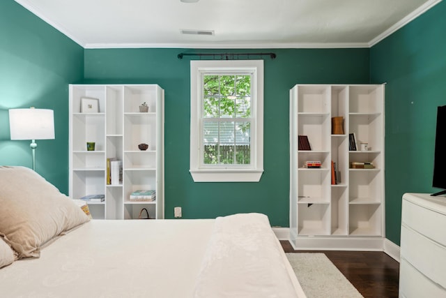 bedroom with dark wood finished floors, baseboards, crown molding, and visible vents