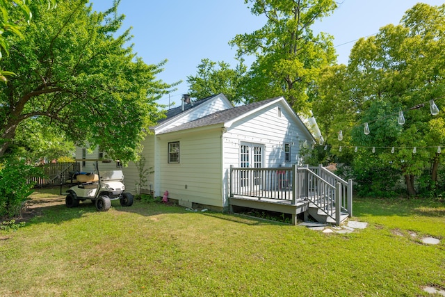 rear view of house featuring a lawn, a wooden deck, a shingled roof, and french doors