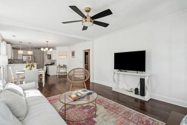 living room with dark wood-type flooring, crown molding, baseboards, and ceiling fan with notable chandelier