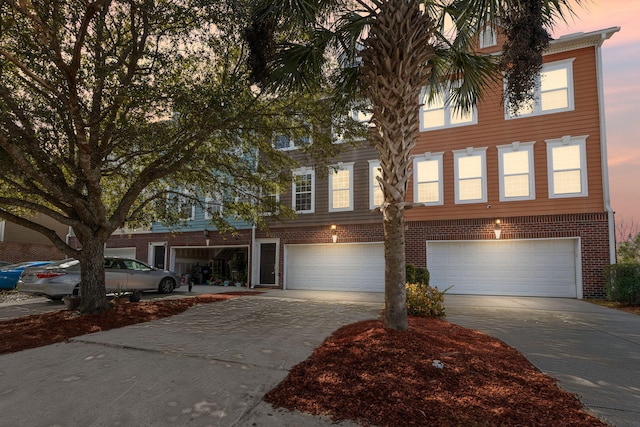 view of front of property with driveway, an attached garage, and brick siding