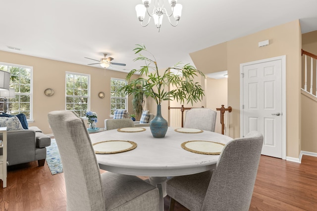 dining area featuring stairway, baseboards, visible vents, and wood finished floors