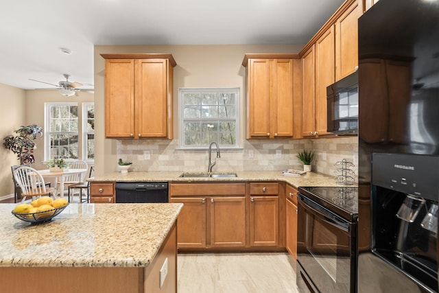 kitchen featuring tasteful backsplash, a sink, black appliances, and light stone countertops