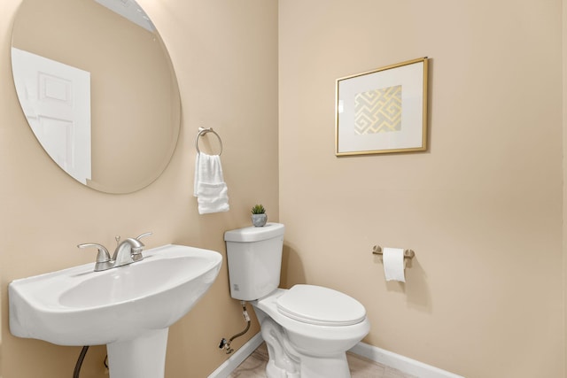 bathroom with a sink, toilet, and baseboards