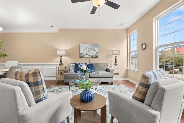 living room with visible vents, wainscoting, ornamental molding, wood finished floors, and a decorative wall