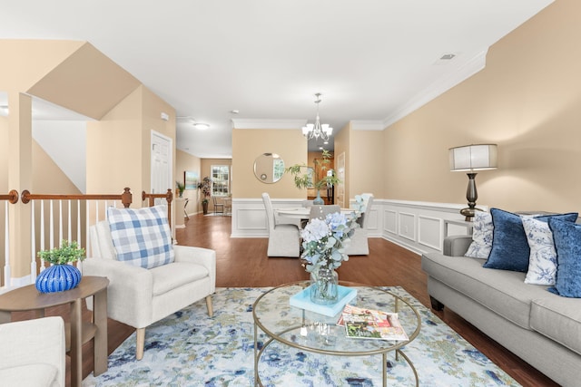 living room with a notable chandelier, a decorative wall, wood finished floors, wainscoting, and crown molding