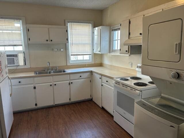 kitchen featuring white appliances, stacked washer / dryer, sink, and white cabinets