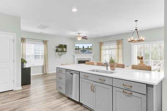 kitchen with dishwasher, gray cabinets, a fireplace, light wood-style floors, and a sink