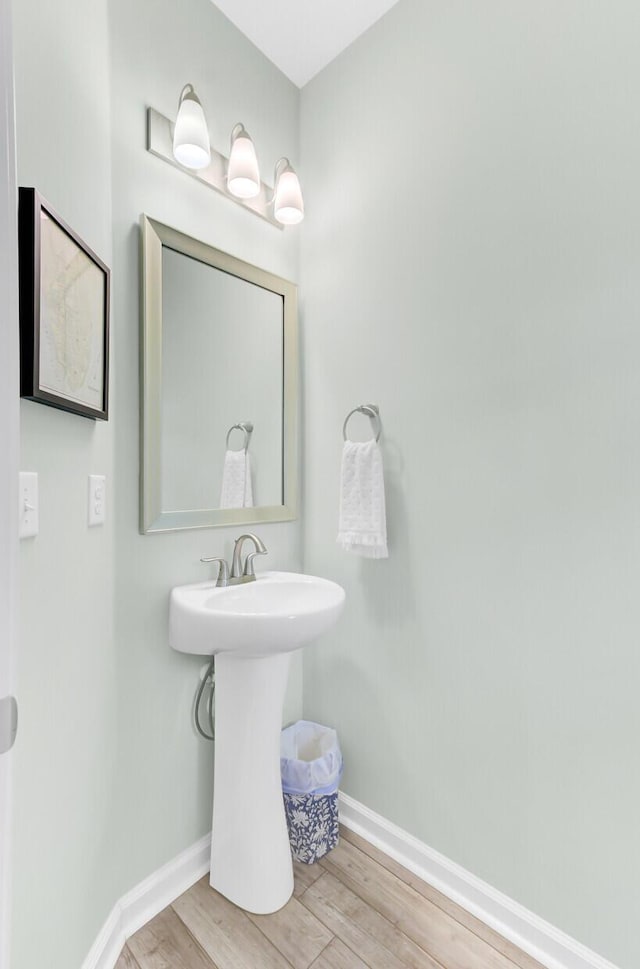 bathroom with wood finished floors, baseboards, and a sink