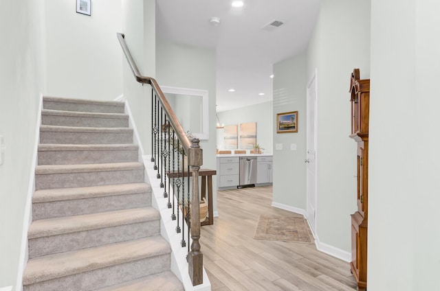 stairway featuring recessed lighting, wood finished floors, visible vents, and baseboards