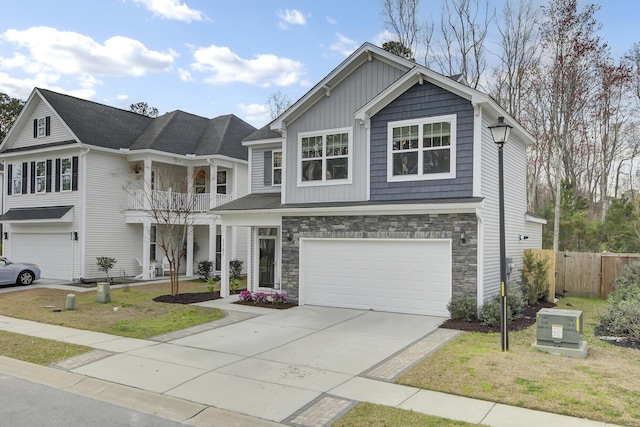 view of front facade with concrete driveway, a balcony, an attached garage, and stone siding