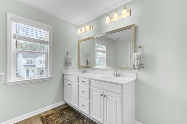 full bathroom with double vanity, wood finished floors, baseboards, and a sink