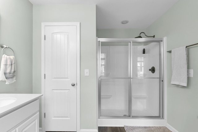 bathroom featuring a shower stall, vanity, and baseboards