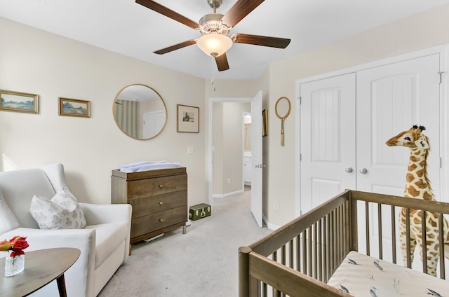 bedroom featuring a closet, light colored carpet, baseboards, and ceiling fan