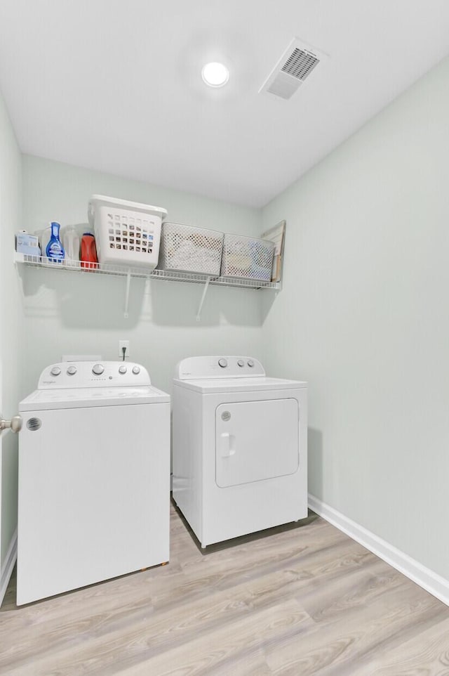 washroom featuring visible vents, baseboards, laundry area, wood finished floors, and washer and dryer