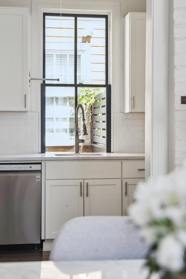 kitchen featuring a sink, dishwasher, white cabinets, and light countertops