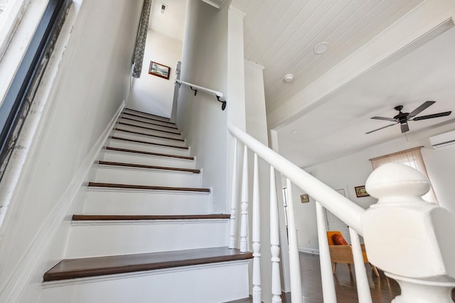 stairs featuring a ceiling fan