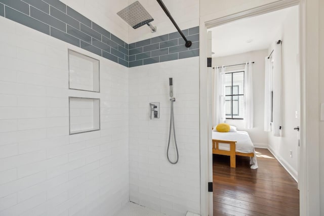 bathroom with baseboards, connected bathroom, hardwood / wood-style flooring, and tiled shower