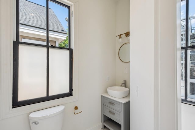 bathroom with toilet, baseboards, and vanity