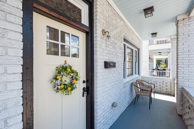 doorway to property featuring covered porch and brick siding