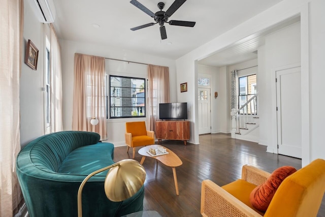 living room with a ceiling fan, wood finished floors, stairway, baseboards, and an AC wall unit