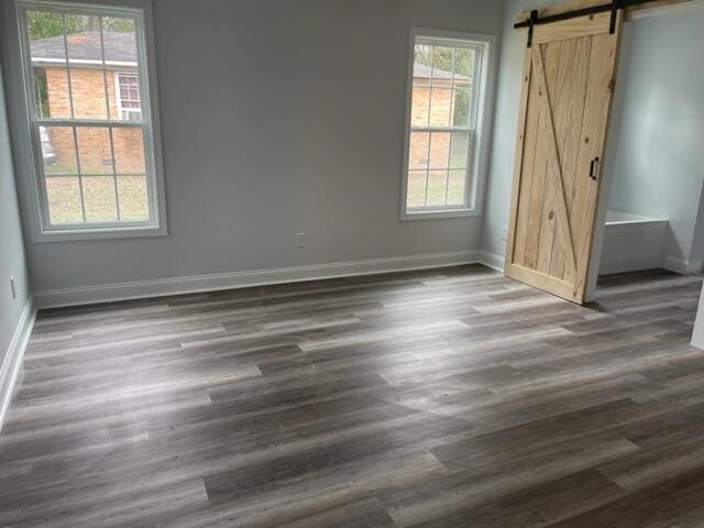 unfurnished room with a barn door and dark hardwood / wood-style flooring