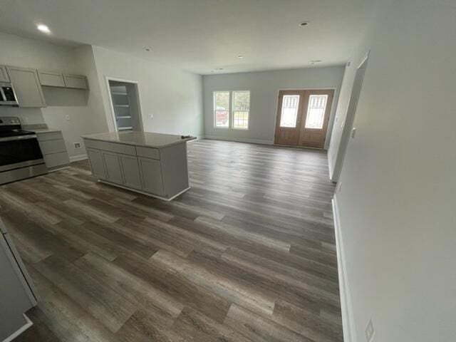 kitchen featuring stainless steel electric range oven, gray cabinets, a center island, french doors, and dark hardwood / wood-style flooring