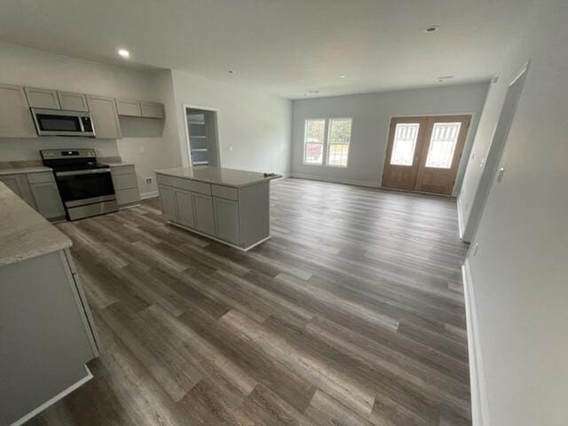 kitchen with dark wood-type flooring, appliances with stainless steel finishes, french doors, a kitchen island, and gray cabinetry