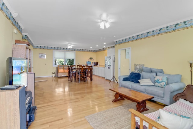 living room featuring crown molding, light wood-style floors, and ceiling fan