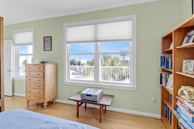 bedroom with crown molding, baseboards, and light wood-type flooring