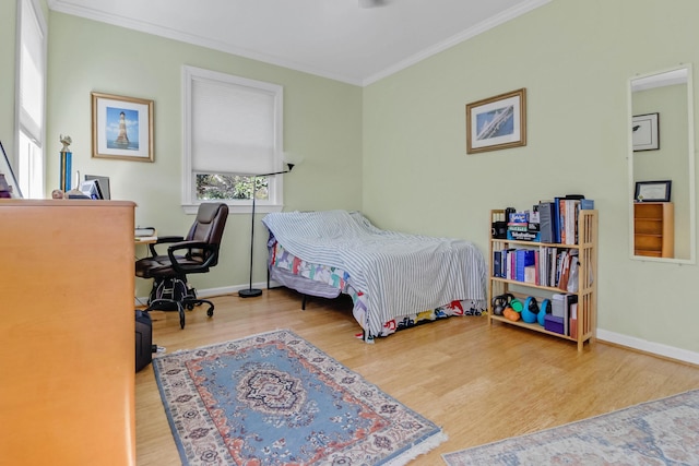 bedroom with crown molding, baseboards, and wood finished floors