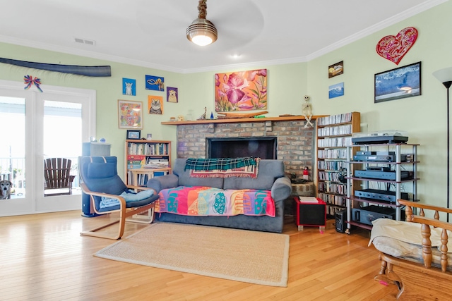 living room with a fireplace, wood finished floors, visible vents, and ornamental molding