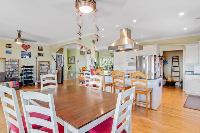 dining area with recessed lighting, light wood-style floors, arched walkways, and ornamental molding