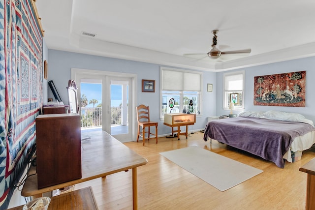 bedroom featuring visible vents, access to outside, wood finished floors, a raised ceiling, and ceiling fan