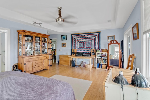 bedroom featuring ceiling fan, a tray ceiling, and wood finished floors