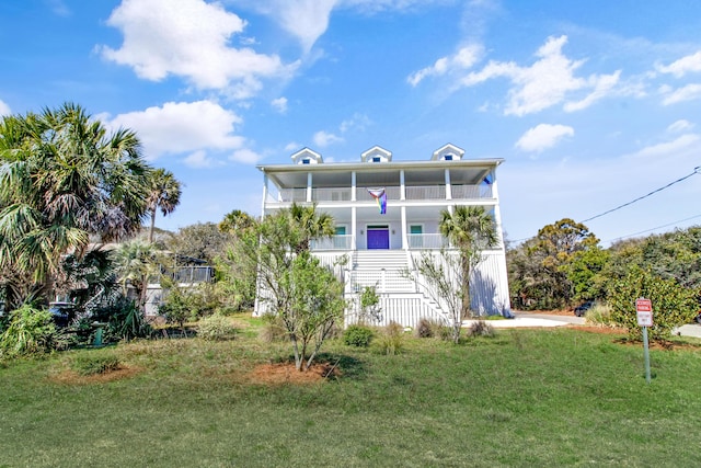 rear view of house with a lawn, a porch, a balcony, and stairs