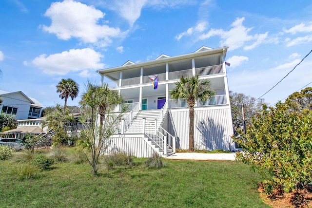 back of property with a lawn, stairs, and a balcony