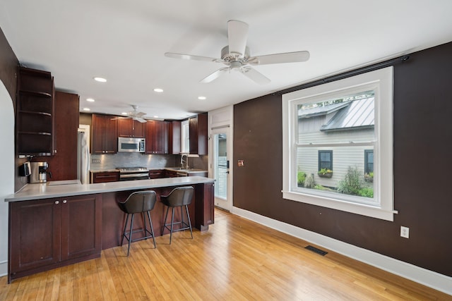 kitchen featuring sink, a breakfast bar, appliances with stainless steel finishes, backsplash, and kitchen peninsula