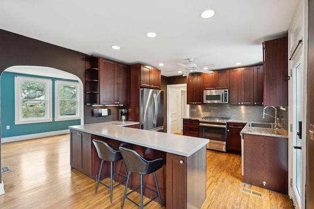 kitchen featuring sink, a breakfast bar, stainless steel appliances, tasteful backsplash, and kitchen peninsula