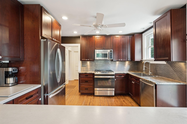 kitchen with stainless steel appliances, sink, light hardwood / wood-style floors, and decorative backsplash