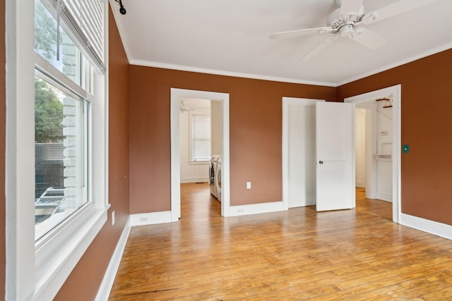 empty room with crown molding, washing machine and clothes dryer, ceiling fan, and light wood-type flooring