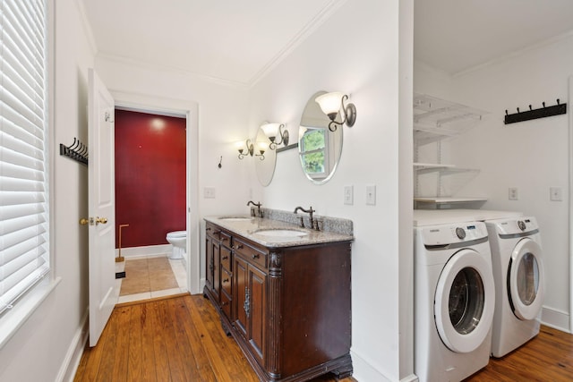 laundry area featuring ornamental molding, separate washer and dryer, sink, and hardwood / wood-style floors