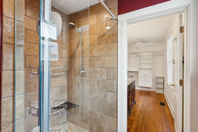 bathroom with ceiling fan, a shower with shower door, and wood-type flooring