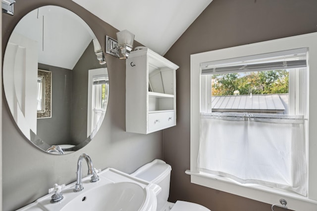 bathroom featuring vaulted ceiling, plenty of natural light, toilet, and sink