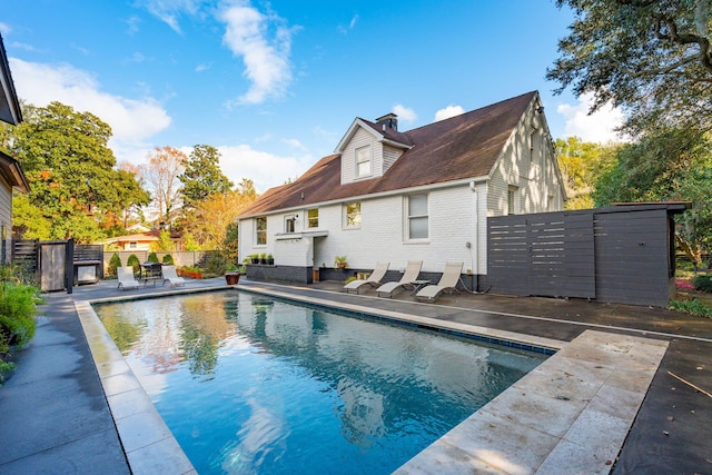 back of house with a fenced in pool and a patio