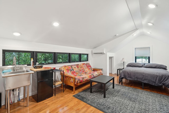 bedroom with black refrigerator, vaulted ceiling, light hardwood / wood-style floors, and a wall mounted AC