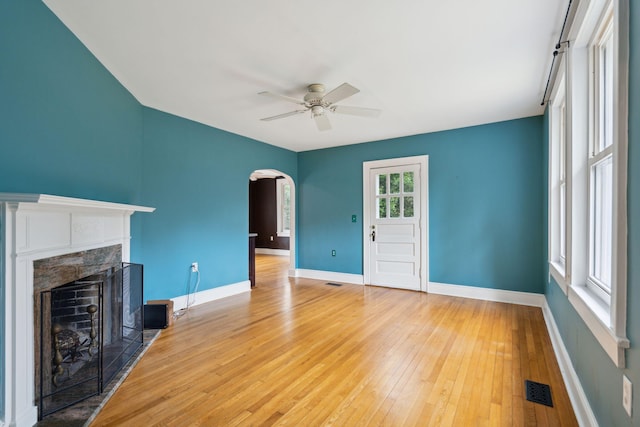 unfurnished living room with a tiled fireplace, hardwood / wood-style floors, and ceiling fan