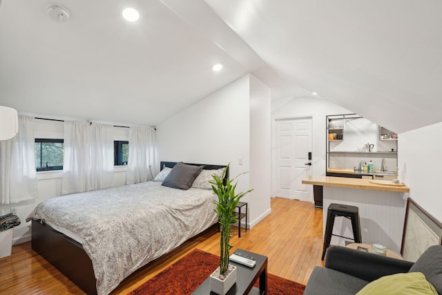 bedroom featuring indoor bar, wood-type flooring, and vaulted ceiling